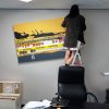 Woman on ladder hanging large yellow canvas hung on clear perlon wires from an ArtiTeq Click Rail picture rail