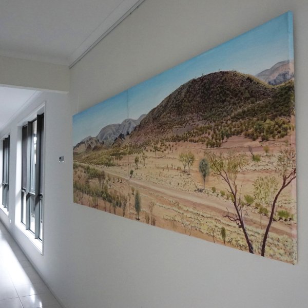 Panoramic Australian landscape canvas hung on clear perlon wires from an ArtiTeq Click Rail Pro picture rail in a bright corridor.