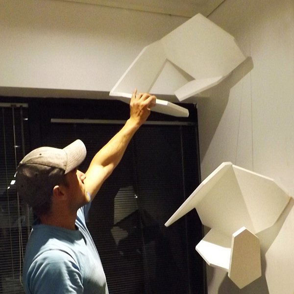 Sculptor installing white geometric sculpture on clear perlon wires from ArtiTeq Click Rail Pro picture rail