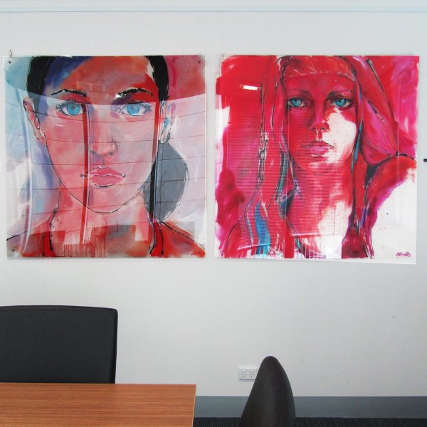 Two vibrant portraits hung on clear perlon wires from ArtiTeq Click Rail Pro picture rail in a modern office