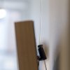 Transparent 1 mm Perlon Twister cable with black Micro Grip hook supporting a timber picture frame, showing minimal forward tilt against the wall.”