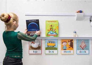 Young girl adjusting educational materials on Artiteq Info Rail +, a versatile display system for modular walls, available at Hang Logic.
