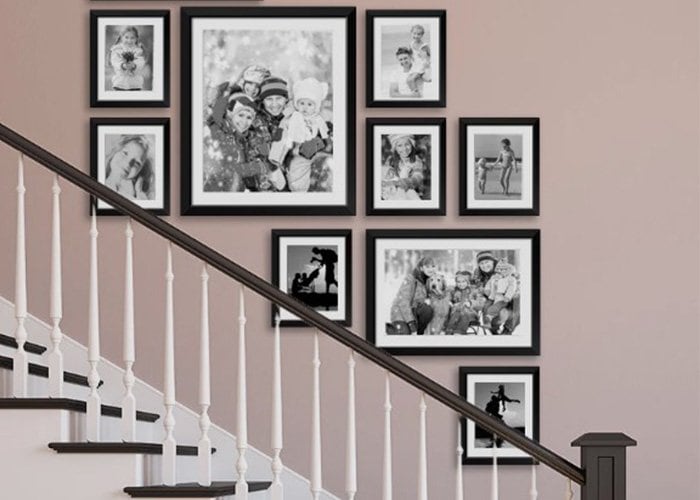 Staircase decorated with a collection of framed family photos using Artiteq's hanging system, provided by Hang Logic.