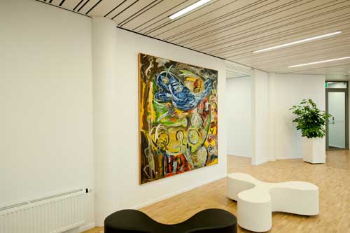 Artiteq picture rail system from Hang Logic mounted on the ceiling, featuring a large colorful painting in a modern interior.