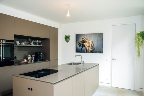 Modern kitchen with Artiteq picture rail system from Hang Logic, featuring sleek cabinets, an island, and a stylish photograph.