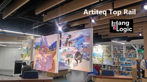 Artiteq Top Rail system displaying paintings at a gallery, sold by Hang Logic, seamlessly integrated into the ceiling for an unobtrusive look.
