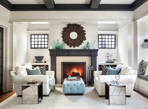Symmetrical Living Room with Fireplace and Blue Accents Symmetrical living room with a fireplace, white armchairs, blue ottoman, and decorative mirror above the mantel.