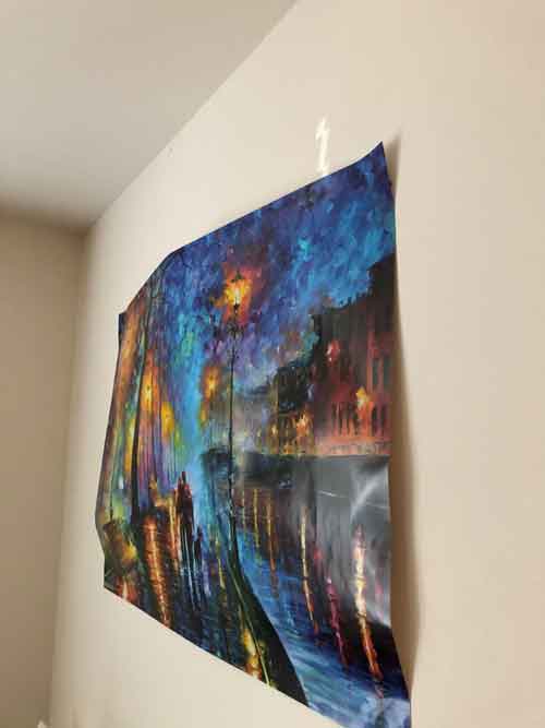 A colourful poster hanging unevenly on a wall, illustrating the issues of improper hanging methods.