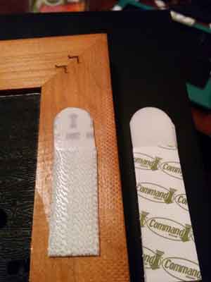 Command Strip attached to the back of a wooden frame for easy wall hanging.