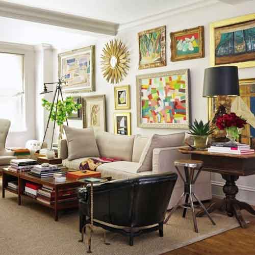 Eclectic living room with a variety of framed art on picture rails, neutral furniture, and colorful decor.