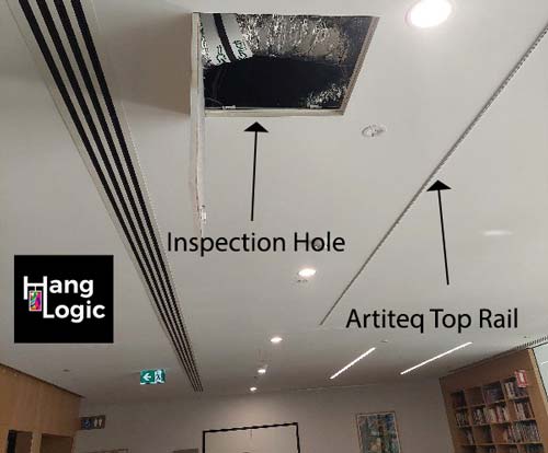 Inspection hole in the ceiling with an Artiteq top rail installed by Hang Logic at ECH Encore Apartments for secure art hanging.