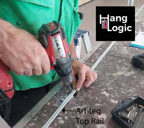 Hang Logic technician pre-drills holes into an Artiteq top rail before ceiling installation at ECH Encore Apartments.