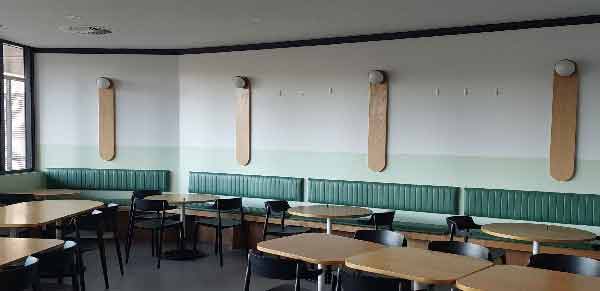 Café area at ECH Encore Apartments with Artiteq picture rails installed by Hang Logic above green seating, designed for flexible art display.