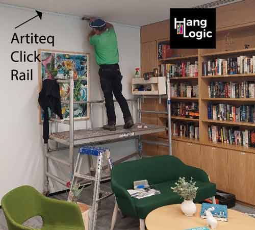 Hang Logic technician installing a picture rail using an Artiteq Click Rail in the library at ECH Encore Apartments.