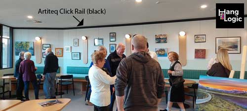 Residents of ECH Encore Apartments admiring artwork displayed using Artiteq picture rails installed by Hang Logic in the café area.