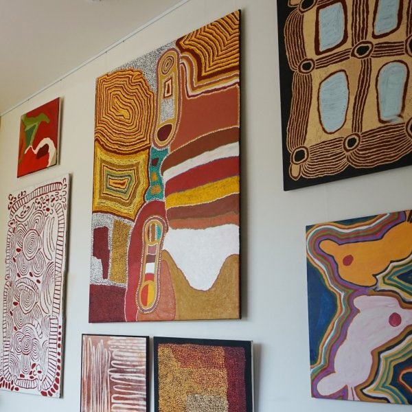 Multiple colourful paintings displayed on a white wall using clear Twister  1mm cables attached to a white ArtiTeq picture rail, supplied by Hang Logic.
