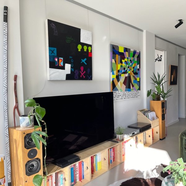 Two colourful canvases above TV hung on clear wires from brushed aluminium Click Rail Pro picture rail in modern lounge room