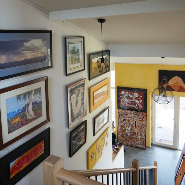 Staircase wall covered with framed art hung on clear Twister Cliq2Fix perlon wires attached to a white ArtiTeq picture rail, supplied by Hang Logic.