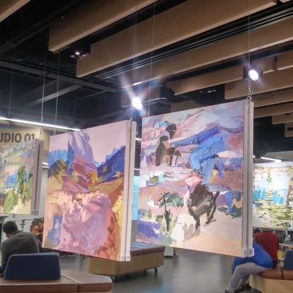 Large square canvases suspended from ArtiTeq Top Rail fixed to timber ceiling baffles in an art studio exhibition space