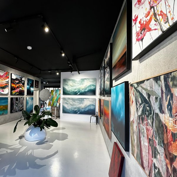 Contemporary gallery with black ceiling; dozens of canvases hung on clear wires from ArtiTeq Top Rail picture rail