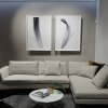 Two framed feather prints above grey sectional sofa hung on clear wires from ArtiTeq Top Rail ceiling picture rail